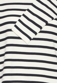 Tissu blanc à larges rayures horizontales bleu marine, présentant une texture côtelée. Le vêtement possède un col rond et des manches longues.