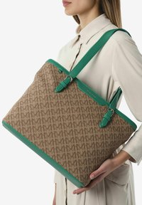Borsa tote con corpo in canvas marrone e motivo a logo intrecciato, con dettagli in pelle verde. Include lunghe tracolle e accessori in metallo.