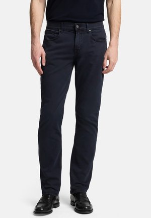 Dunkelblaue Baumwollhosen im Slim-Fit-Schnitt, mit Fünf-Taschen-Design, Knopfverschluss und dezenten Stickdetails. Tragen mit schwarzen Lederschuhen.