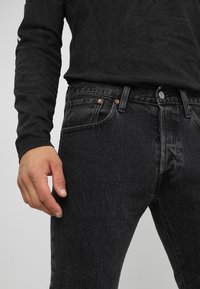 Svarta denimjeans med en åtsittande design, som har kontrastsömmar, framfickor och detaljer i kopparfärg. Strukturerad tyg med lätt blekning.