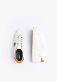 Weiße Wildledersneaker mit dunkelblauer Markenlogo, strukturiertem weißen Gummisohle und orangefarbigem Akzent an der Ferse. Klassisches Schnürdesign.