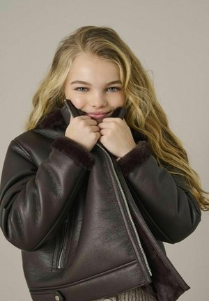 Giubbotto di pelle marrone scuro con colletto e polsini foderati in pelliccia. Presenta una zip frontale e tasche laterali. Texture liscia, design ampio e rilassato.