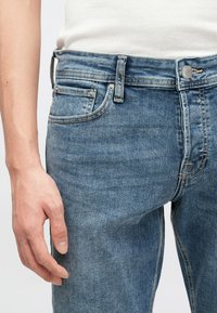 Τζιν παντελόνια σε μεσαίο μπλε ξέβγαλμα με σχεδιασμό πέντε τσεπών. Διαθέτουν μεταλλικό κουμπί κλεισίματος και ορατή ραφή. Ομαλή υφή με ελαφριά ξεθώριασμα.