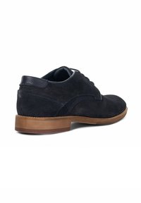 Navy suede dress shoes with a rounded toe, minimal stitching, and a tan rubber sole. Features a smooth leather heel accent.