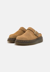 Brown suede clogs with a rounded toe, adjustable strap, and contrasting yellow stitching on a thick rubber sole.