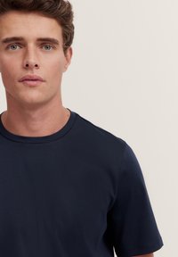 Navy blue short-sleeved t-shirt with a crew neckline, made from smooth fabric, fitted design, and subtle stitching details near the shoulders.