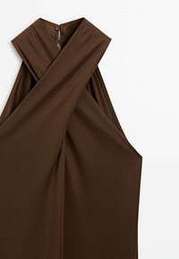 Haut sans manches en ribbed marron avec un col plié, comportant trois boutons décoratifs à l'arrière et une silhouette ouverte et drapée.