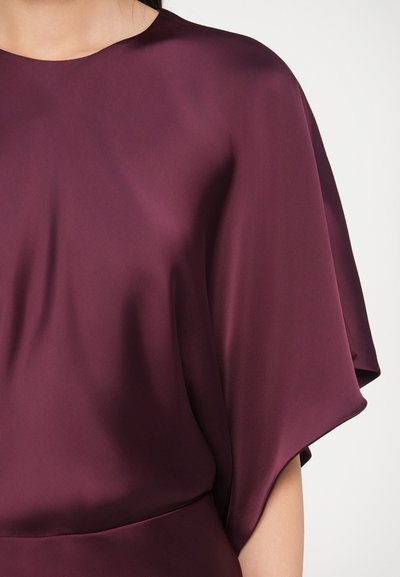 Rochie din satin burgundy cu textură fină, mâneci largi și decolteu rotund. Țesătura cade delicat pe corp.