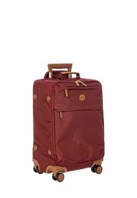 Valigia color bordeaux con esterno in tessuto, manico retrattile e dettagli marroni. Quattro ruote per la mobilità e tasca con zip anteriore per il ripostiglio.