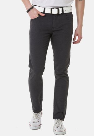 Graue, strukturierte Hose mit schlankem Schnitt, vorderen Taschen und einem weißen Gürtel. Kombiniert mit weißen Sneakers, ergibt dies ein lässiges Outfit.