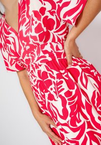 Bloemenjurk met een roze en witte print, korte mouwen, een v-hals en een geplooide taille voor een mooie pasvorm. Zachte, lichtgewicht stof.