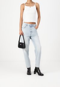 Vit ribbad kort topp med scallopkrage, ihop med ljusblå hög midja jeans och svarta ankelskor. Bär en liten svart handväska.