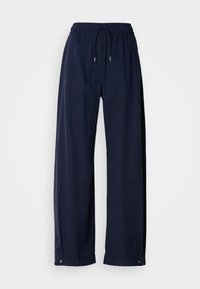 Pantalons larges bleu marine en matériau doux. Comprend une taille élastique avec cordon de serrage et des accents métalliques au niveau de l'ourlet.