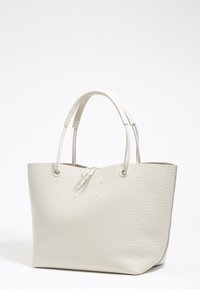 Witte leren tote bag met textuur, twee korte handgrepen en een open bovenkant. Heeft een ronde vorm en een minimalistisch ontwerp.