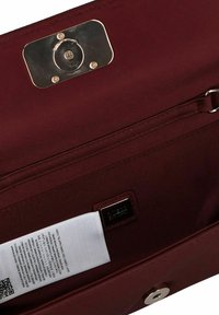 Interiores de un bolso burdeos que incluyen un cierre de hardware plateado, forro de tela, etiqueta y un bolsillo con cremallera. Textura suave con costuras limpias.