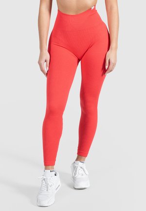 Hoge taille legging in ribbed rode stof, met een strakke pasvorm en een zachte textuur, gecombineerd met witte sport sneakers.
