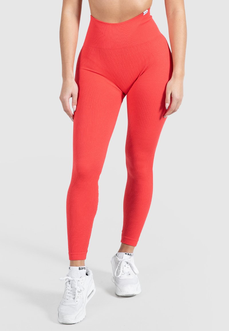 Hoge taille legging in ribbed rode stof, met een strakke pasvorm en een zachte textuur, gecombineerd met witte sport sneakers.