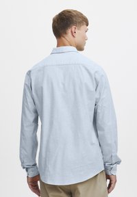 Lichtblauwe blouse met lange mouwen, gemaakt van katoen, met een button-down kraag, knoopmanchetten en een gebogen zoom.