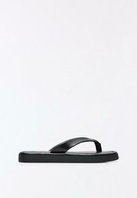 Schwarze minimalistische Flip-Flop-Sandale mit breiten Lederriemen und flacher, leicht gepolsterter Sohle vor weißem Hintergrund.