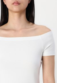 Biela, tričko bez ramienok s krátkymi rukávmi, priliehavý strih, hladká textura a priame výstrih. Minimalistický štýl, jednofarebné.