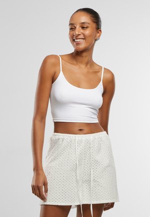 White cropped tank top with thin straps paired with white shorts featuring a textured eyelet pattern and drawstring waistband.