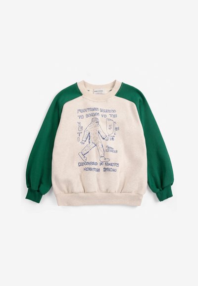 Sweat-shirt enfant avec manches vertes et corps beige, avec un croquis bleu d'un yéti et un texte sur les empreintes du yéti et la découverte.