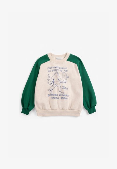 Sweat-shirt enfant avec manches vertes et corps beige, avec un croquis bleu d'un yéti et un texte sur les empreintes du yéti et la découverte.