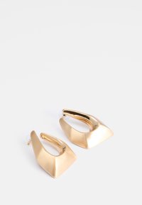 Boucles d'oreilles en métal doré avec une finition lisse et polie ; design asymétrique comprenant une forme arrondie et géométrique ; attaches transparentes.