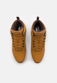 Brown leather high-top sneakers with round toe, featuring lace closure, padded collar, and memory foam insole. SKECHERS logo on tongue.