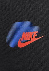 Tela negra con un diseño gráfico que presenta franjas horizontales azules y un prominente logo rojo de Nike, enfatizando colores audaces y una textura moderna.