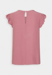 Blouse rose à manches courtes avec manches à volants et ouverture dos en forme de goutte d'eau sécurisée par un petit bouton au niveau de l'encolure.