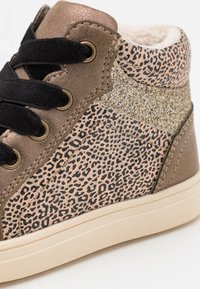 Braune Kunstleder-Sneaker mit Leopardenmuster, goldenen Glitzer-Akzenten, schwarzen Schnürsenkeln und beiger Gummisohle. Strukturierte Oberfläche mit weichem Futter.