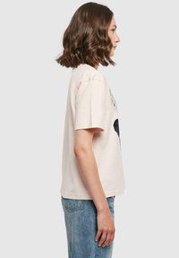 Lyserød bomulds T-shirt med rund hals, korte ærmer og grafisk print på fronten, paired med højtaljede blå jeans.