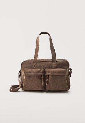 Sac à épaule et à main en velours côtelé marron avec deux poches avant zippées, doubles poignées et une bandoulière latérale réglable sur fond blanc.