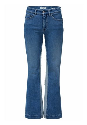 Vaqueros azules de mezclilla con piernas anchas y paneles de bordes sin rematar que corren verticalmente a lo largo de los lados exteriores de cada pierna.