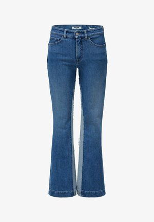 Vaqueros azules de mezclilla con piernas anchas y paneles de bordes sin rematar que corren verticalmente a lo largo de los lados exteriores de cada pierna.