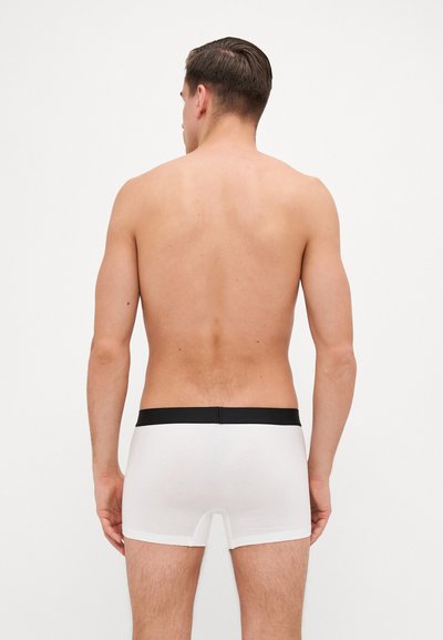 Boxeri din bumbac alb cu un tiv elastic negru, având o croială strânsă și o textură netedă, prezentând vederea din spate a modelului.