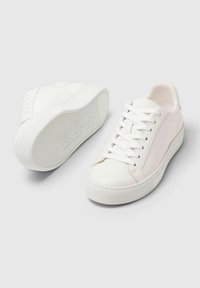 Bijele kožne tenisice s glatkom površinom, okruglim vrhom i ravnim gumeni potplatom. Imaju vezice i suptilno označavanje sa strane.