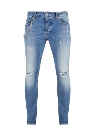 Mršavi plavi traperice s izblijedjelim pranjem, s istrošenim dijelovima i rupama na koljenima. Uključuju srebrni lanac detalj pričvršćen u struku.