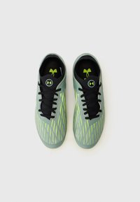 Scarpe da ginnastica verde chiaro con lacci neri, caratterizzate da un design testurizzato e dettagli in giallo neon sui lati, forma complessivamente affusolata.