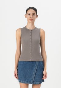 Sivi rebrasti top bez rukava s gumbima, uparen s denim suknjom na preklop. Tkanina je glatka, a boje su neutralne.