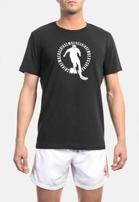 Zwarte katoenen t-shirt met korte mouwen, voorzien van een witte grafische afbeelding van een speler en tekst in een cirkelontwerp. Gladde textuur, klassieke pasvorm.