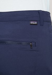 Pantalones azul marino con una textura suave, que cuentan con un bolsillo con cremallera y una etiqueta con el logo de Patagonia en la cinturilla.