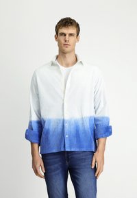 Wit en blauwe gradient shirt met een gestructureerd patroon, knoopsluiting aan de voorkant, opgerolde mouwen en een casual pasvorm, gedragen met donkere jeans.