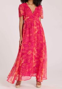 Maxi-jurk in levendig roze met abstracte oranje patronen, korte mouwen, V-hals en knoopdetail aan de voorkant; lichtgewicht, vloeiende stof.