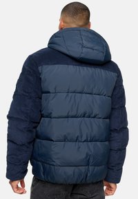 Navy puffer jacket with a hood, featuring quilted sections and soft corduroy accents on the shoulders and sleeves.