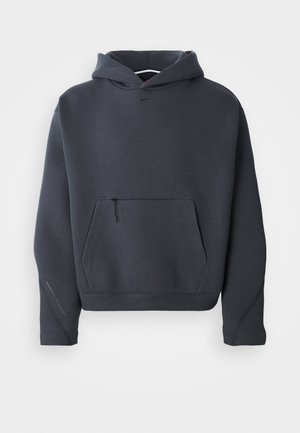 Sweat à capuche gris foncé en tissu doux, avec une poche avant zippée, des poignets côtelés et un petit logo sur la poitrine.
