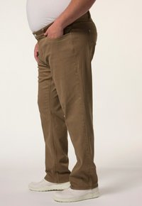 Pantaloni marroni a gamba dritta realizzati in cotone, con un classico design a cinque tasche, passanti per la cintura e chiusura con bottone. Indossati con sneakers bianche.