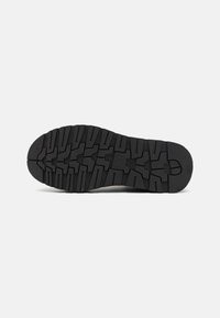 Suola di scarpa in gomma con un motivo di battistrada robusto, superficie texture e colore nero. Il design garantisce aderenza e durata.