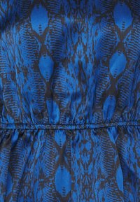 Tessuto blu e nero a motivo con design simile a un rettile, caratterizzato da una texture liscia e dettagli arricciati in vita.